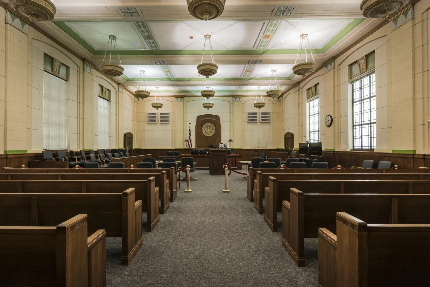 Rows of wooden pews facing the bench in a federal courtroom.